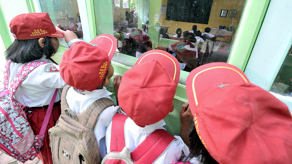 Sejumlah murid sekolah dasar melihat proses belajar murid baru (kelas 1) dari luar kelas di SDN Suko no 363 kecamatan Sukodono, Sidoarjo, Senin (14/7). Hari pertama masuk sekolah yang bertepatan dengan bulan Ramadhan, pelajaran murid kelas 1 jam 7 sampai jam 8, kelas 2 jam 8 sampai jam 10. ANTARA FOTO/Hendra Sonie/EI/Koz/ama/14.