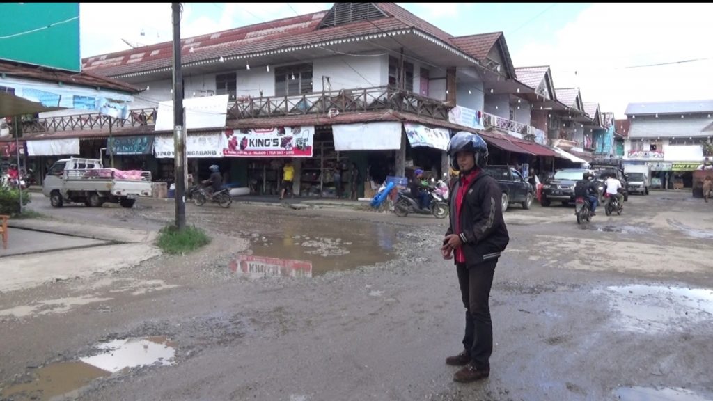 Seorang warga saat melihat genangan air dititik jalan rusak dikomplek pasar baru Ngabang rabu (16/1)