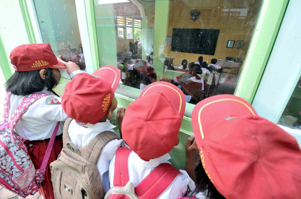 Sejumlah murid sekolah dasar melihat proses belajar murid baru (kelas 1) dari luar kelas di SDN Suko no 363 kecamatan Sukodono, Sidoarjo, Senin (14/7). Hari pertama masuk sekolah yang bertepatan dengan bulan Ramadhan, pelajaran murid kelas 1 jam 7 sampai jam 8, kelas 2 jam 8 sampai jam 10. ANTARA FOTO/Hendra Sonie/EI/Koz/ama/14.